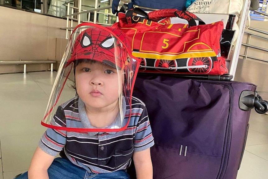 A young boy sits on an airport trolley