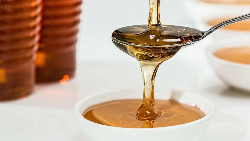 Honey pouring down from a spoon.