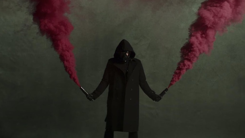 Video grab from the Architects 'Animals' music video; hooded figure with smoke flares