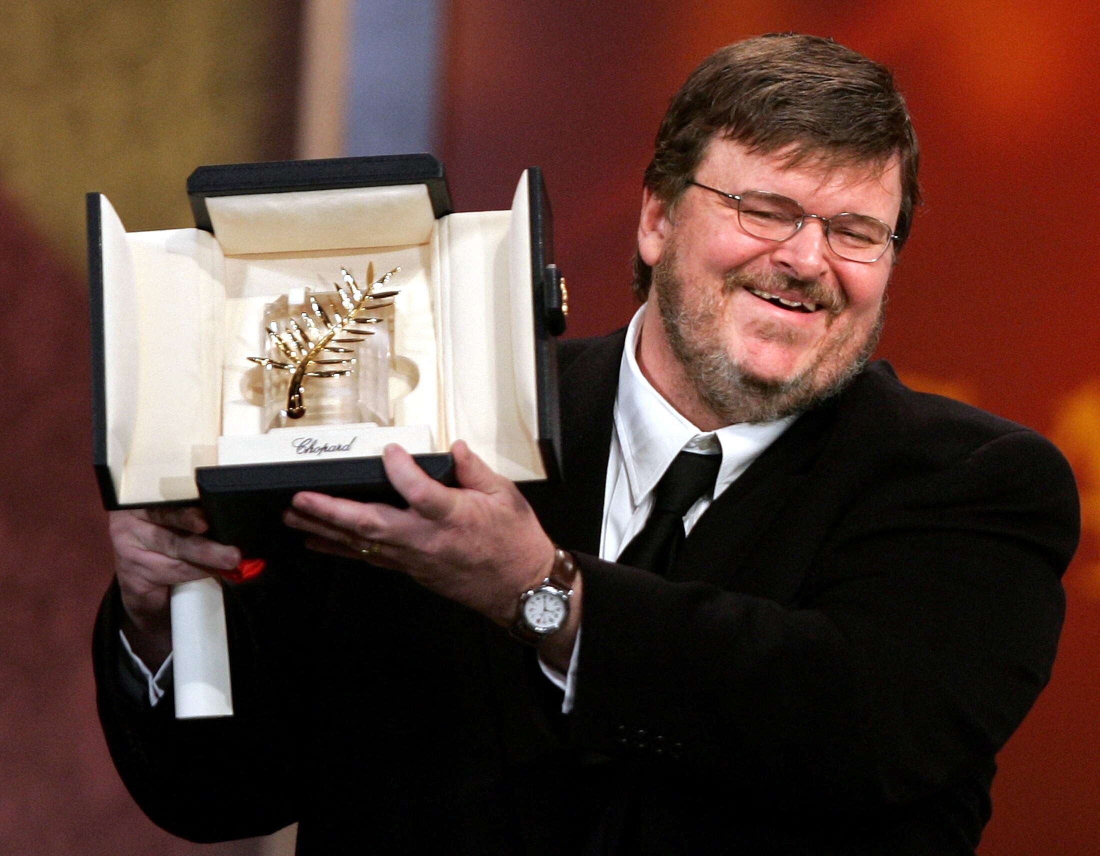 Michael Moore holding a palm shaped trohpy. 