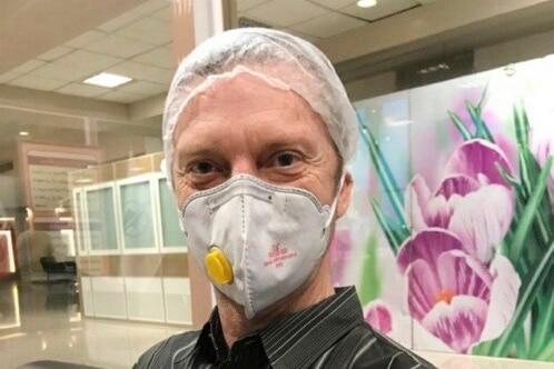 US  Navy veteran Michael White wears a mask and hairnet appears to be smiling.