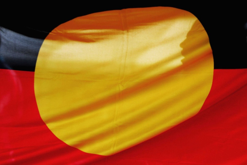 A woman is silhouetted behind the Aboriginal flag in Sydney, May 2006.