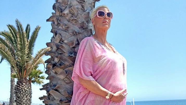 Brigitte Nielsen poses by the beach, holding her pregnant belly.