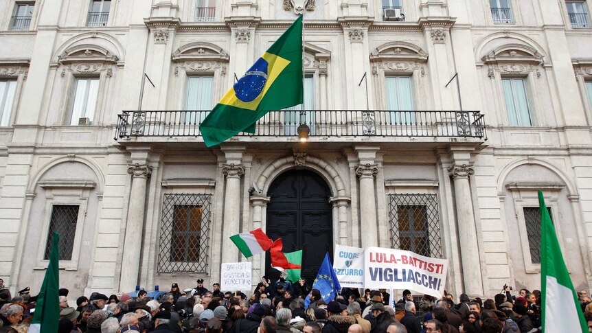A large crowd of protesters with EU and Italian flags protest in front of the neoclassical Brazilian embassy in Rome.