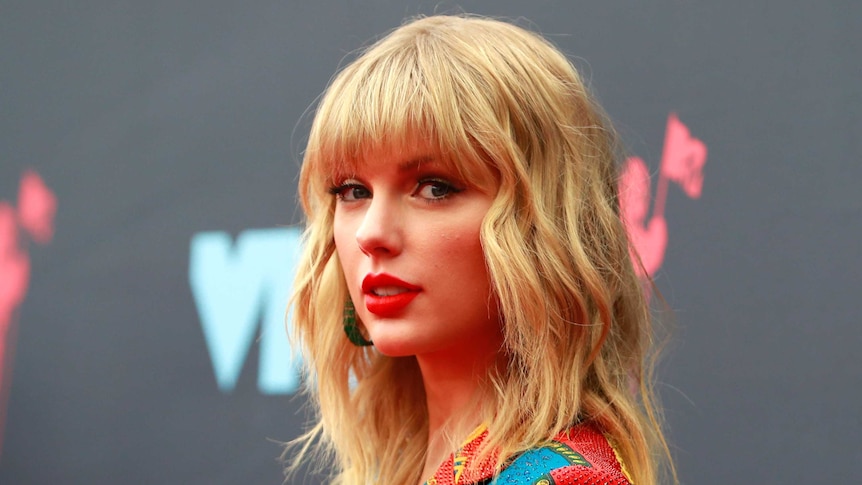 Taylor Swift looking sideways at the camera, wearing a colourful jacket.