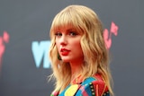 Taylor Swift looking sideways at the camera, wearing a colourful jacket.