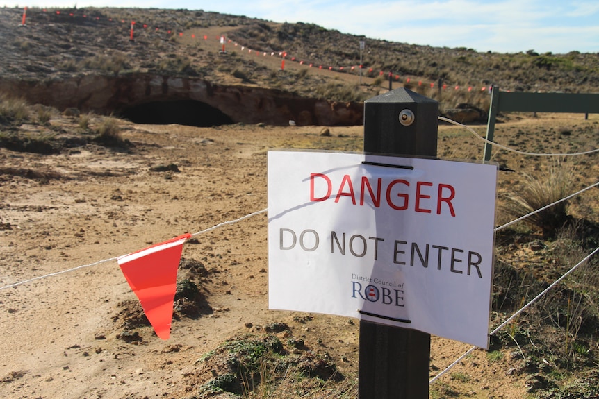 A laminated paper sign reading 'Danger do not enter' with rocky cliffs behind