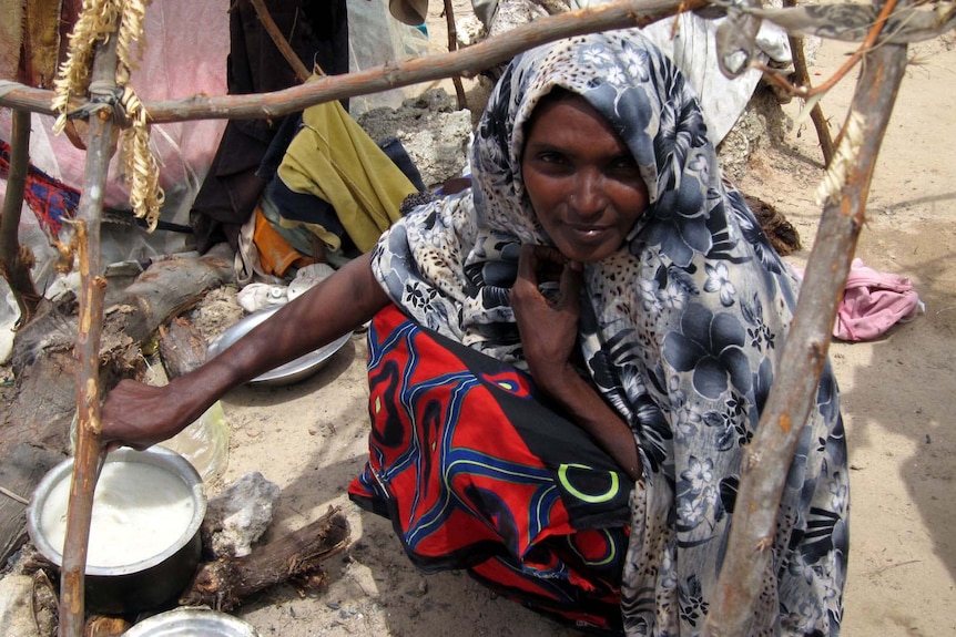 The woman prepares porridge for her children at the camp.