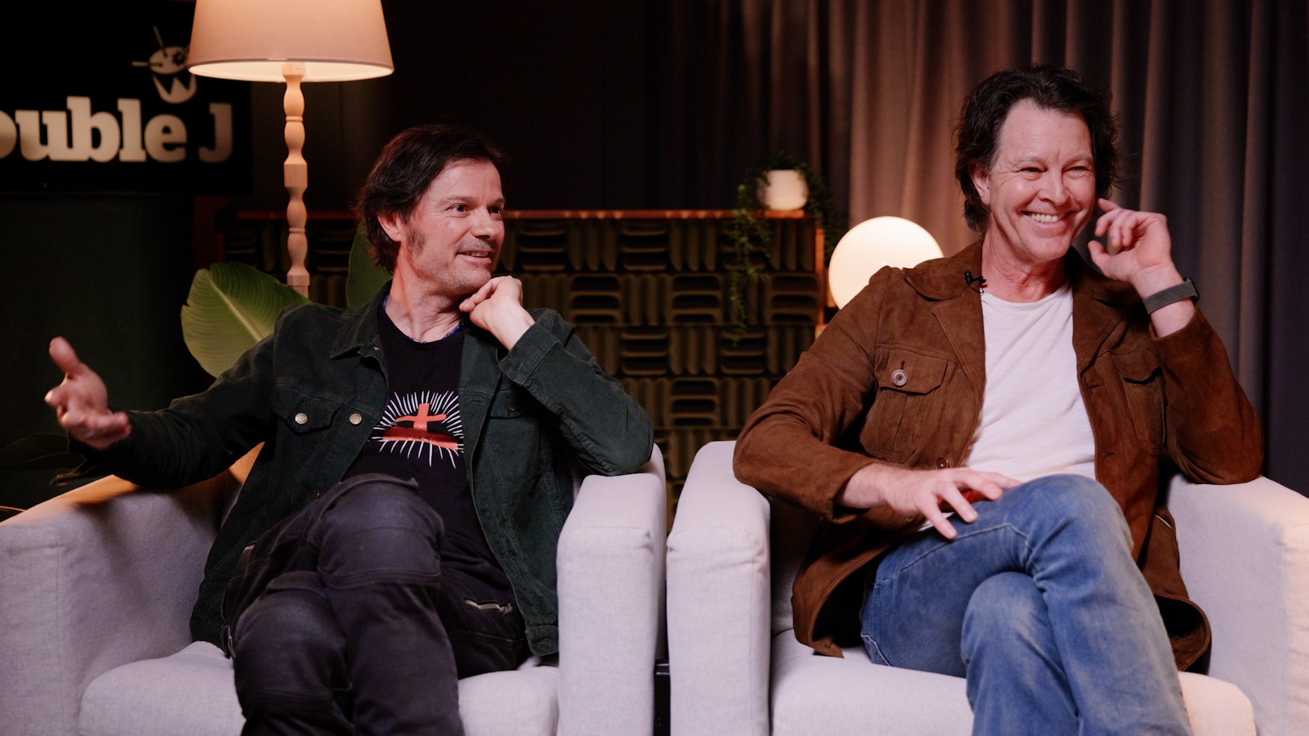 Darren Middleton and Bernard Fanning sit side by side, smiling, on armchairs.