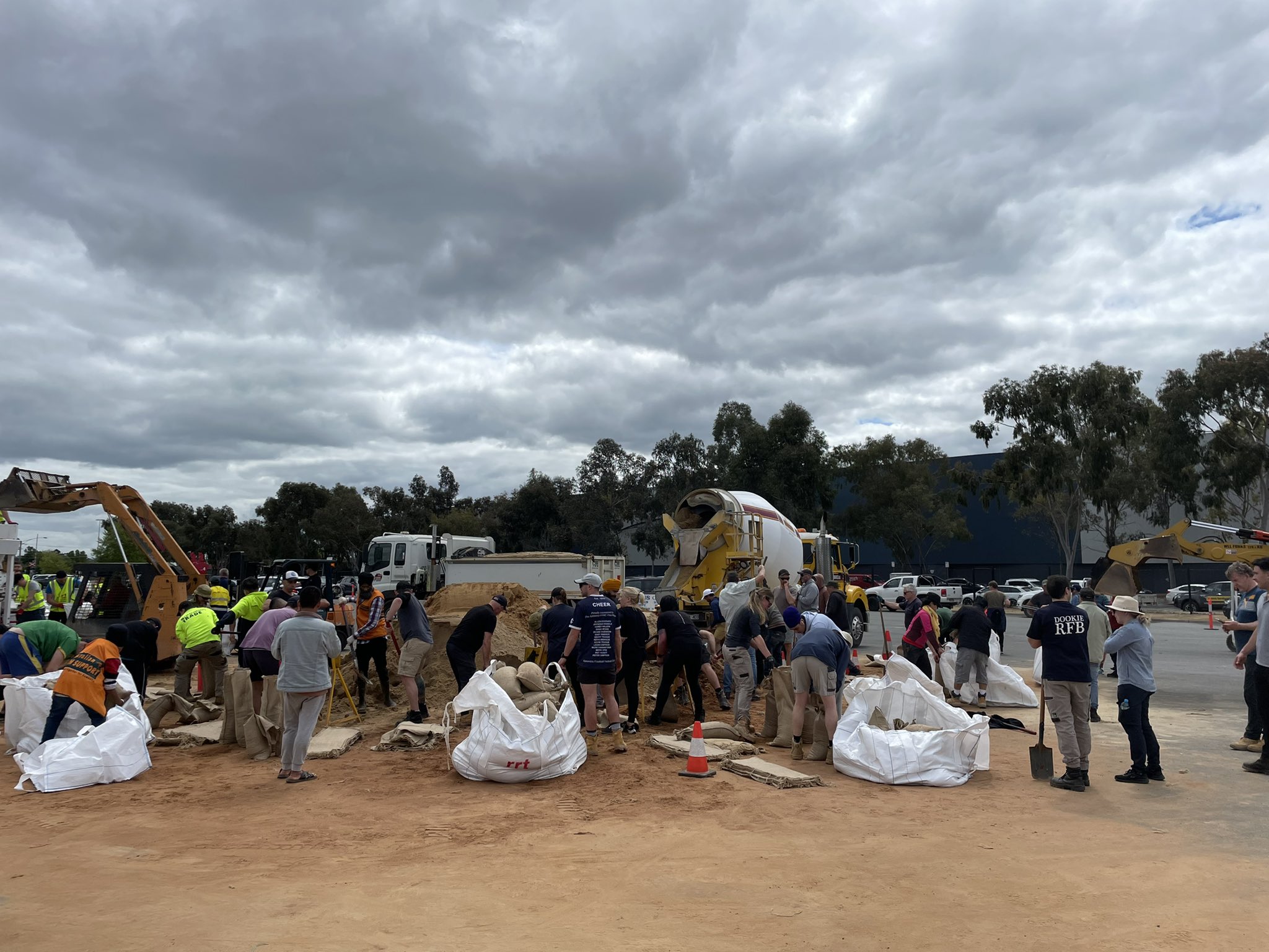 Dozens of people fill sand bags on the side of the road. 
