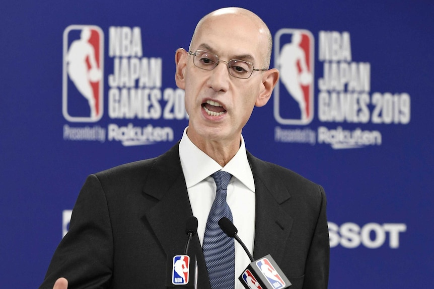 A top basketball executive speaks as he stands in front of microphones at a press conference.