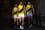 The Richmond Tigers walk out of a tunnel underneath a stadium before a game.