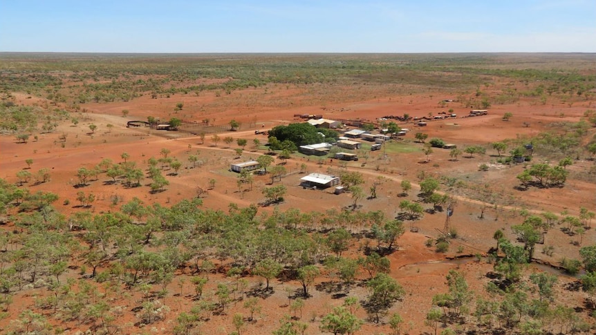 a homestead in the middle of red dirt and trees.