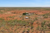 a homestead in the middle of red dirt and trees.