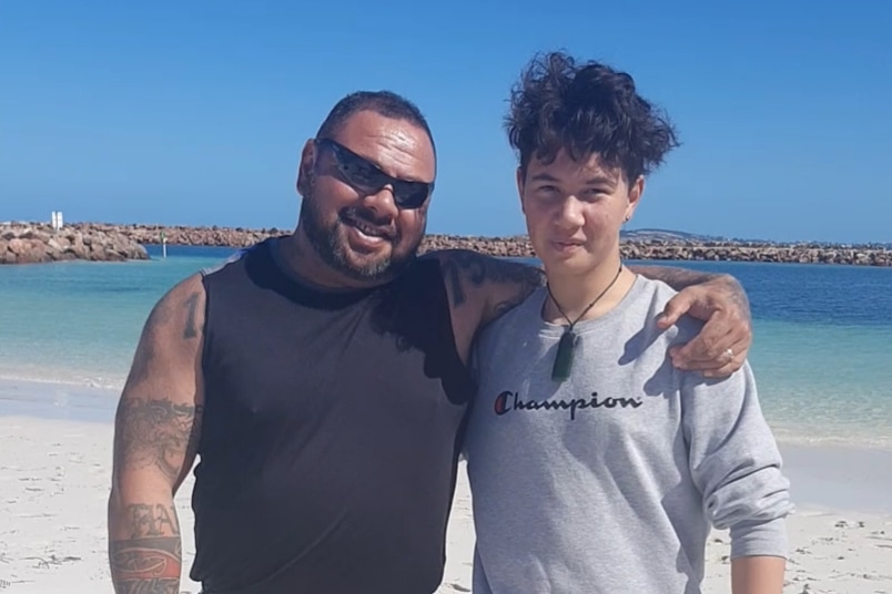 Father Shannon Tana has an arm around his son's shoulder at the beach.