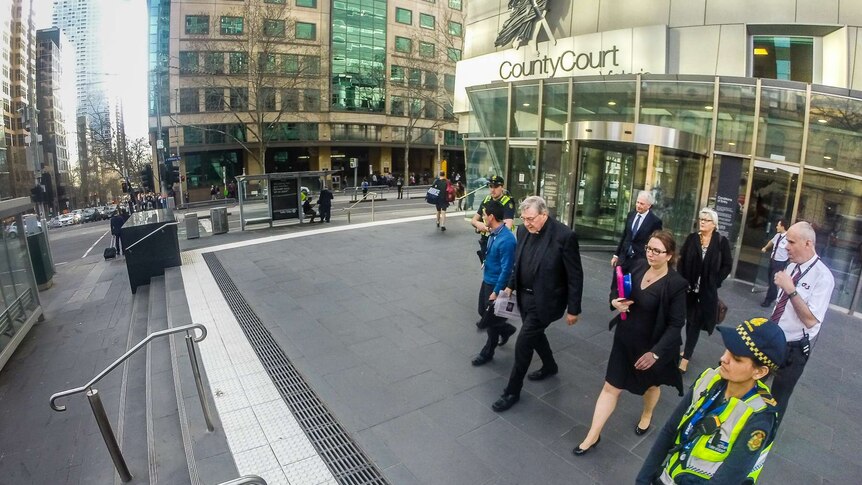 George Pell outside the County Court with police and lawyers.