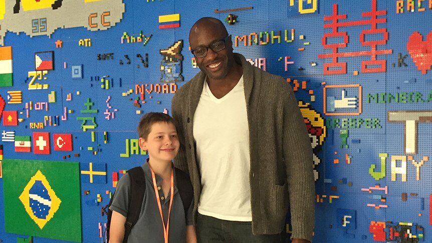 Hamish Finlayson stands with Facebook's Ime Archibong in front of a wall covered in Lego.