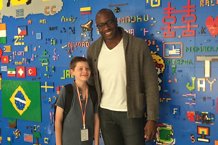 Hamish Finlayson stands with Facebook's Ime Archibong in front of a wall covered in Lego.