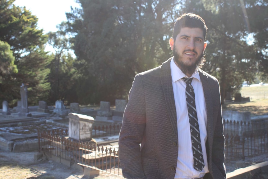 Jameel Qureshi standing near graves at Blayney's cemetery