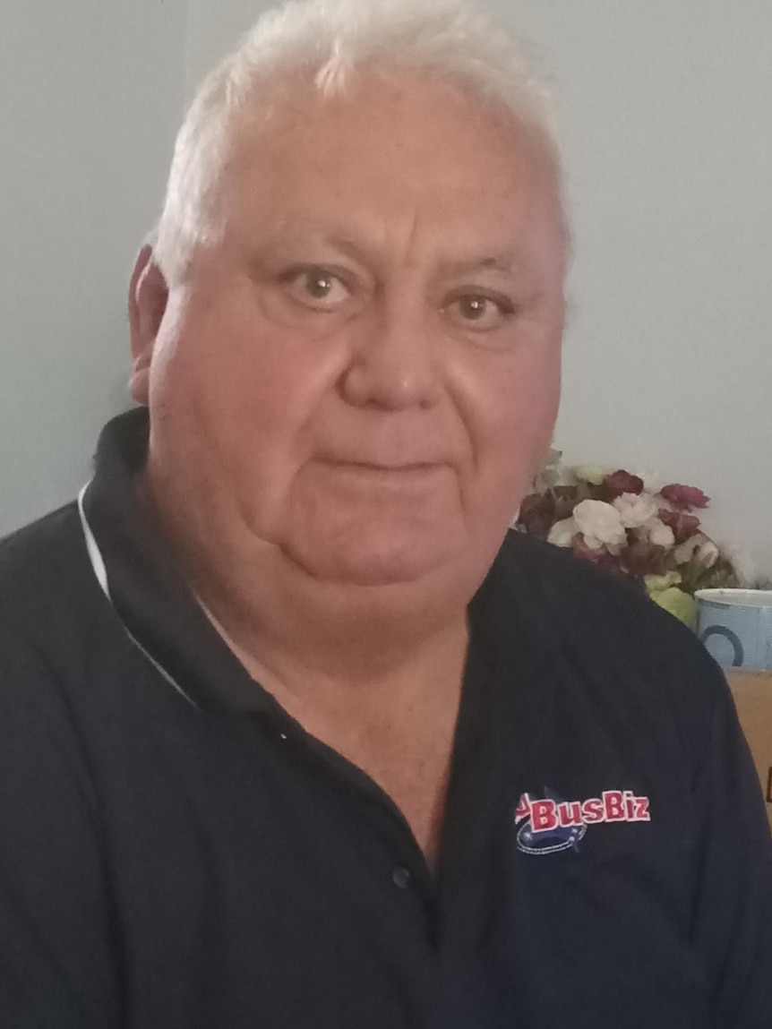 An Aboriginal man with white hair looks at the camera.