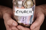 A jar with Church written on it full of money.