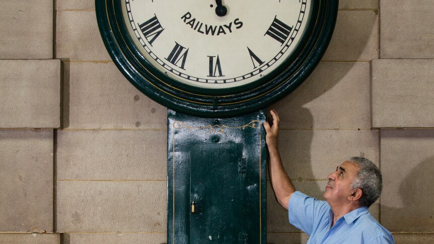 Mr Minty standing next to a platform clocks at Sydney Central station's grand concourse.