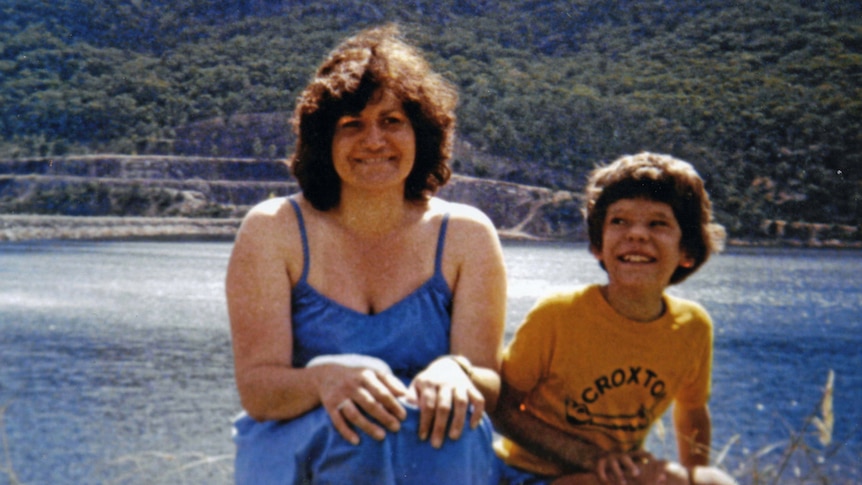 Maria and young Adam sit in front of a lake