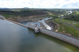 An aerial photo of Paradise Dam wall with water flowing into the Burnett River