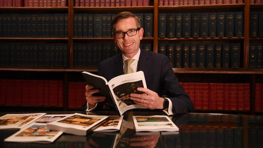 A man holding a book smiles at the camera.