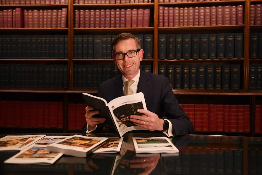 A man holding a book smiles at the camera.