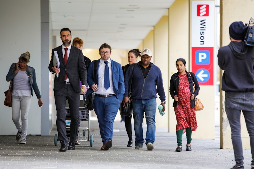 A wide shot showing Aishwarya Aswath's parents walking along a footpath next to two men, including  