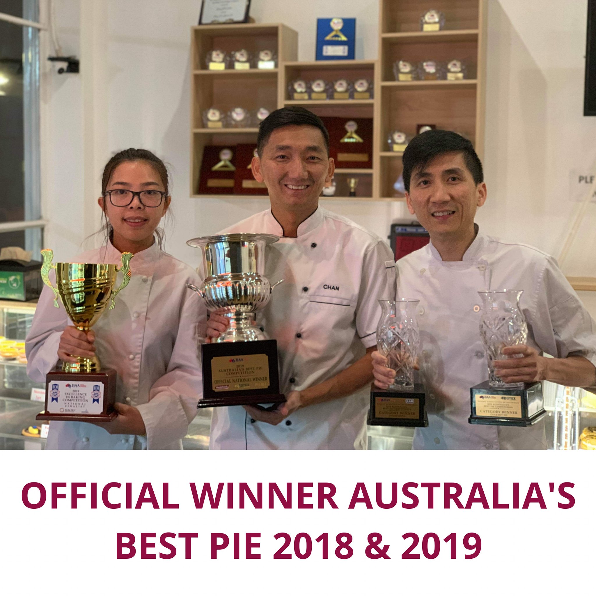 A woman and two men dressed in crisp white baking uniforms hold up trophies and awards.