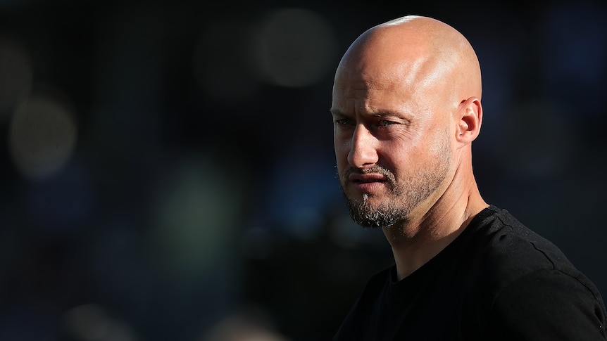 A bald man in a black t-shirt looking intense.