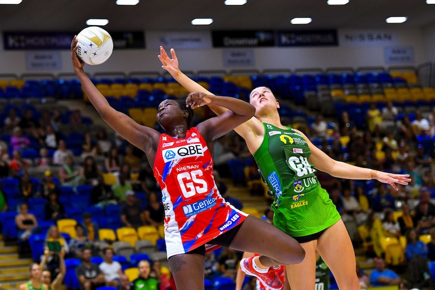 Sam Wallace catches a netball in one hand as Courtney Bruce stretches one hand up next to her