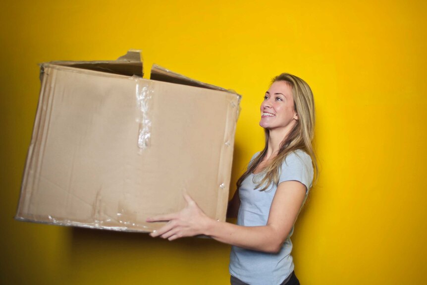 Woman carrying a cardboard box for a story about tips to make moving house easy.