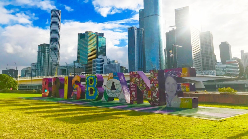 Sunlight streams through Brisbane sign with city building in background at South Bank in CBD