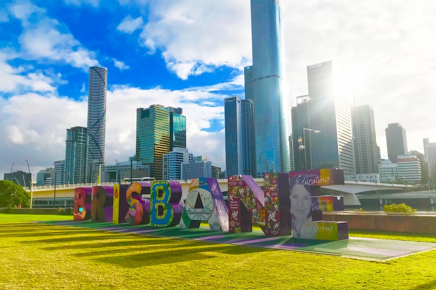 Sunlight streams through Brisbane sign with city building in background at South Bank in CBD