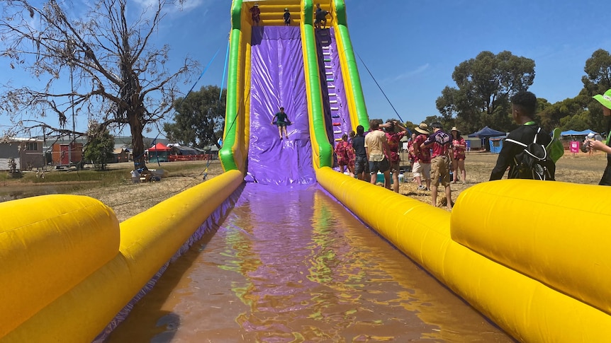 big yellow water slide, blow up, with a child going down it