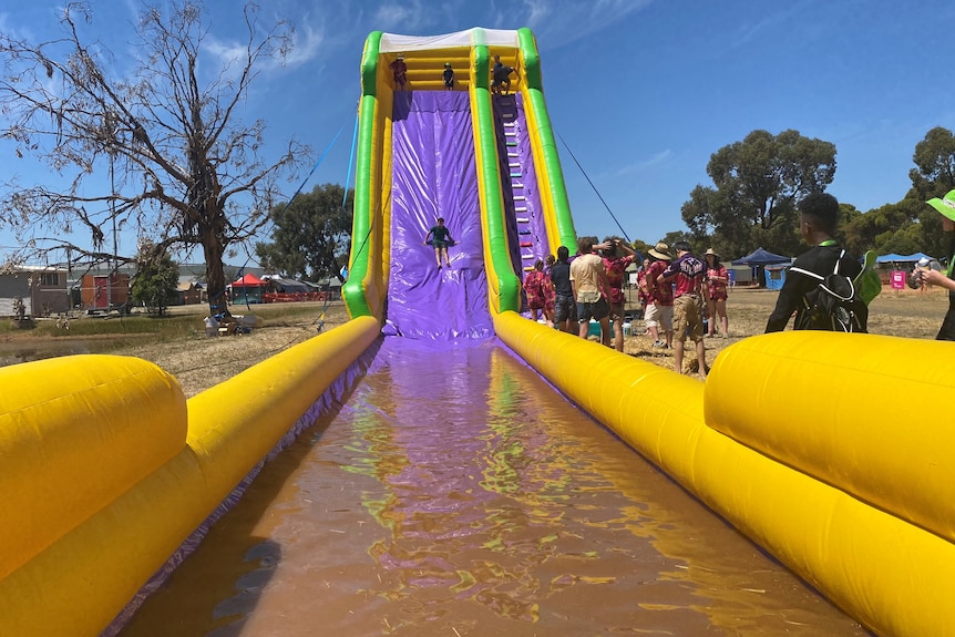 large yellow water slide, blast up, with a child walking down it