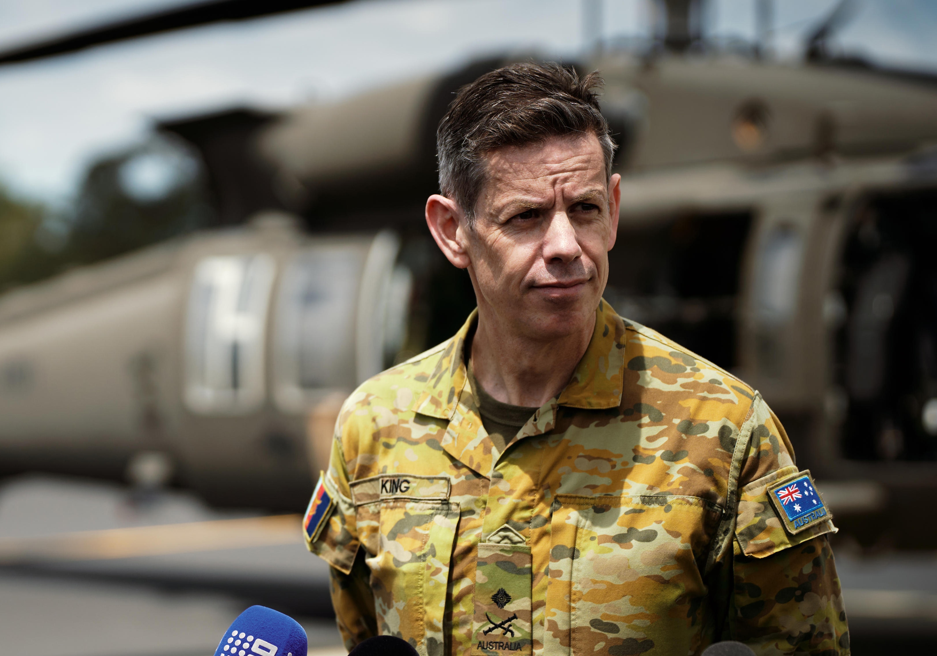 a middle-aged man wearing army uniform squinting in the sun