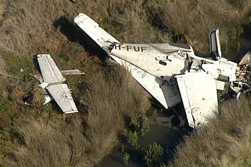 An aerial image of a badly damaged small plane in a ditch.