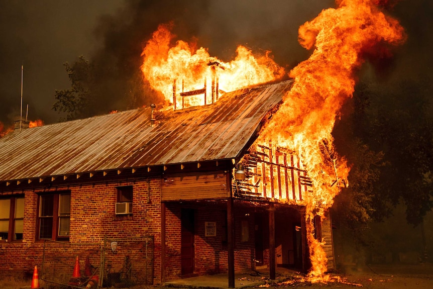 Flames burst from the roo of an old brick building.