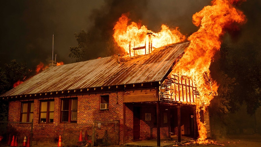 Flames burst from the roo of an old brick building.