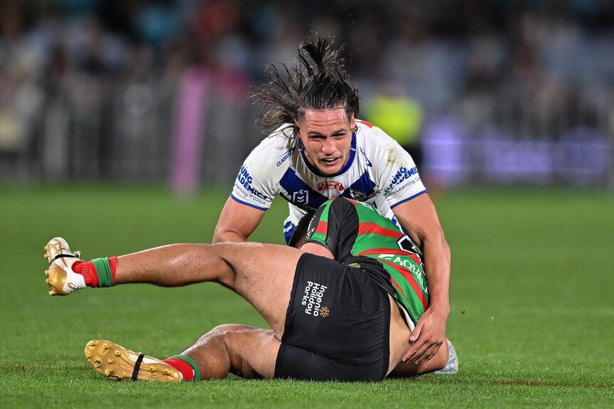 NRL player Jackson Topine, lying on top of an opponent after tackling them