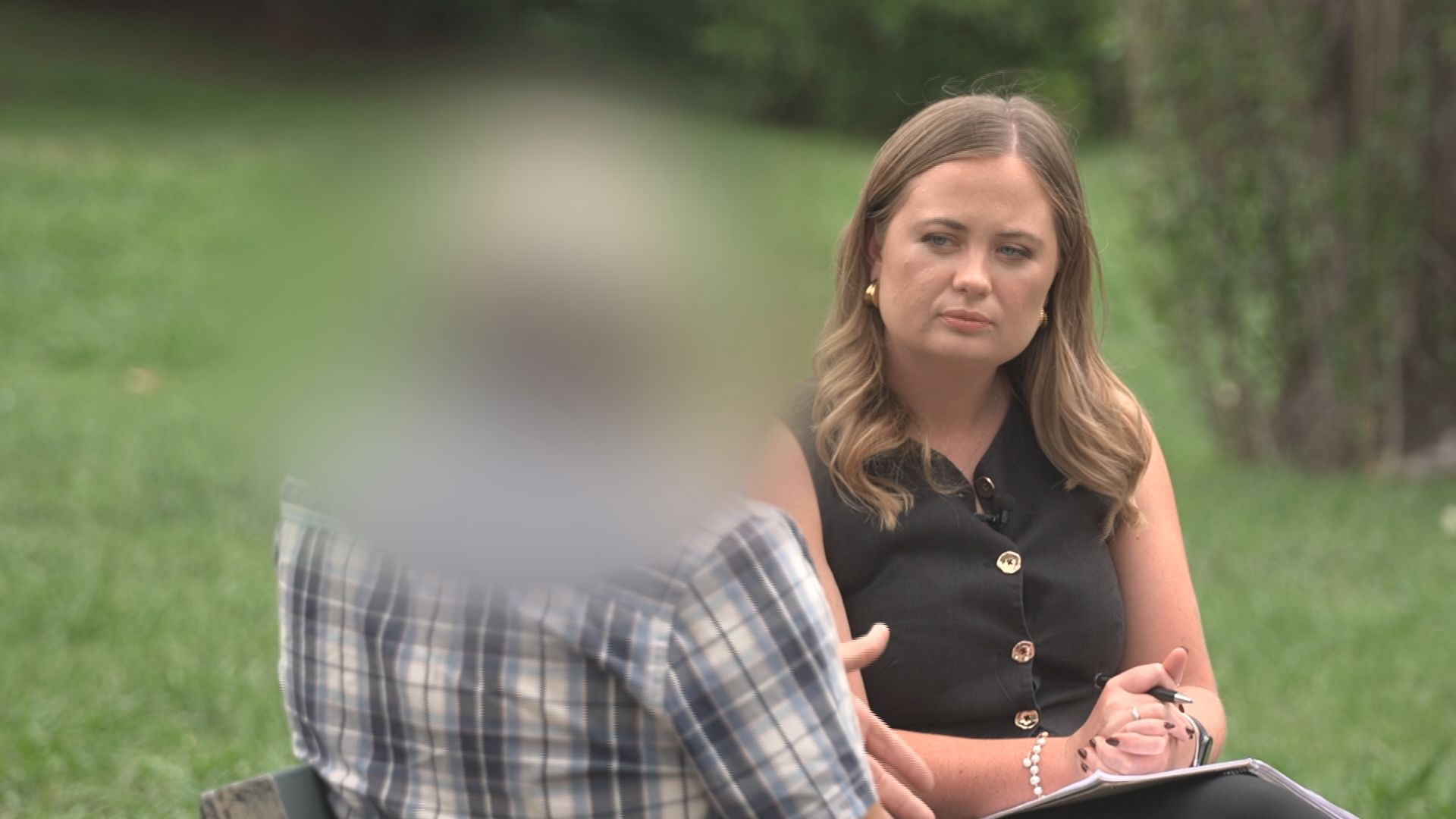 blurred man speaking to a woman on a park bench