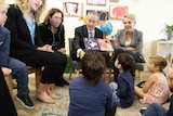 Bill Shorten reads a book to children sitting on the floor below him. He's surrounded by his Labor colleagues