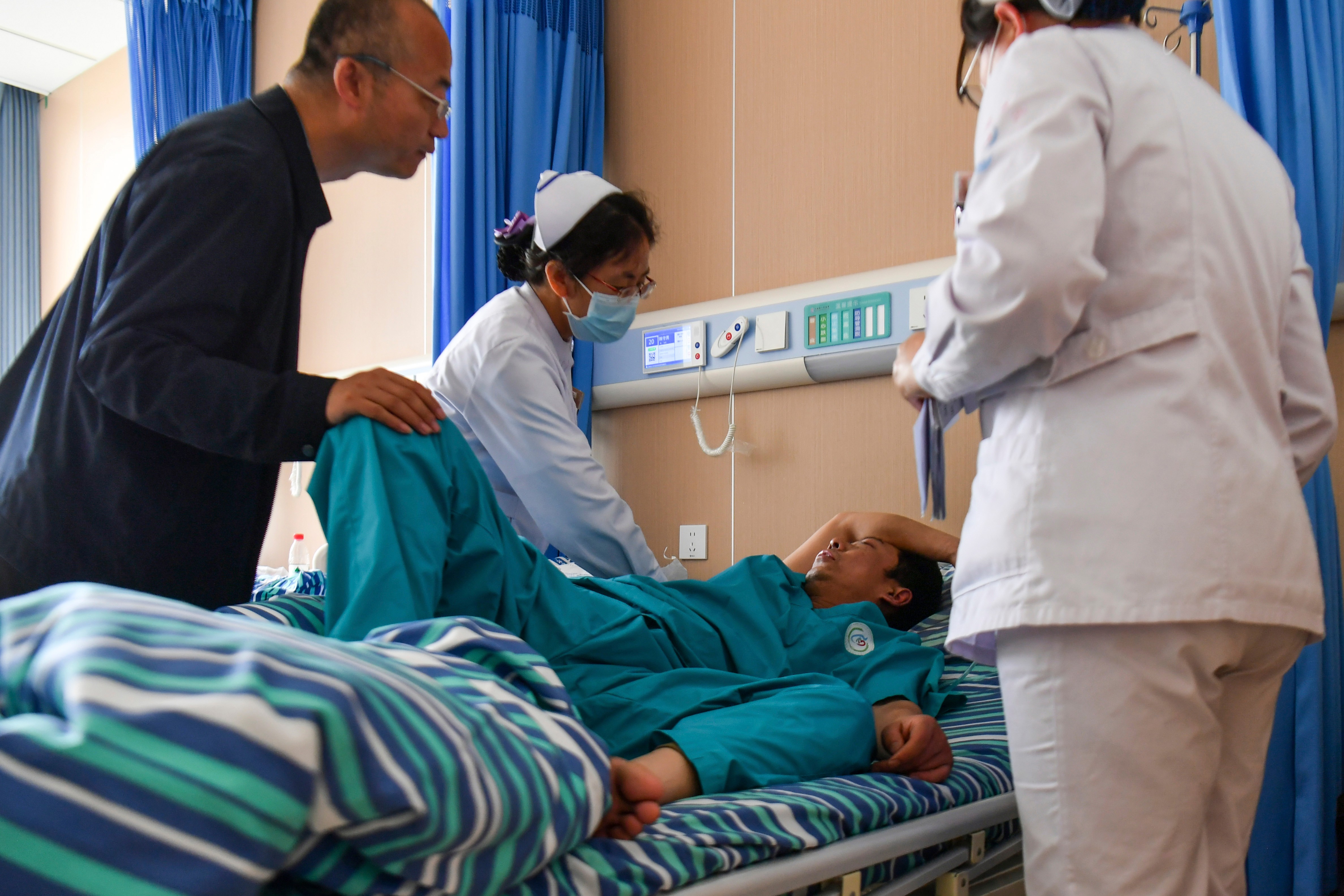 A man and woman tend to a patient in hospital.