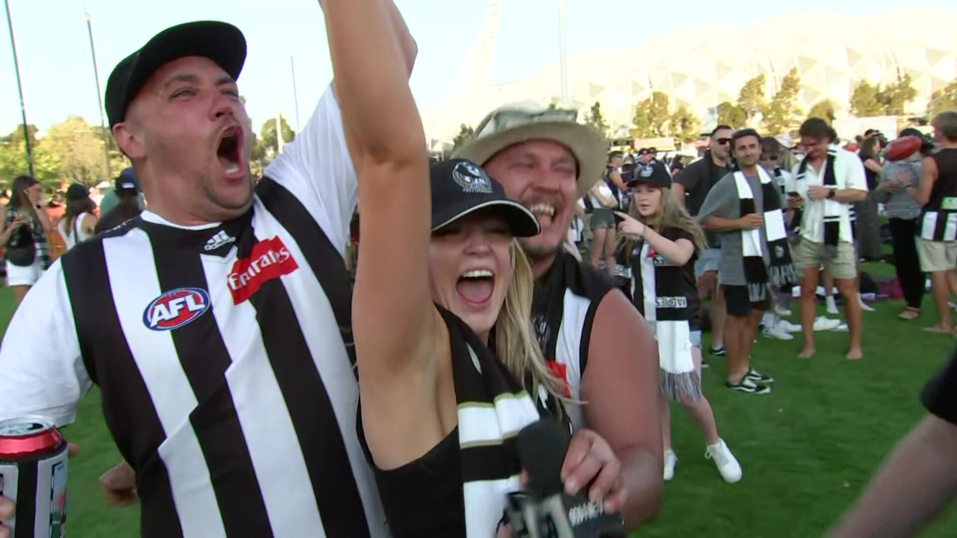 People dressed in Collingwood attire celebrate.
