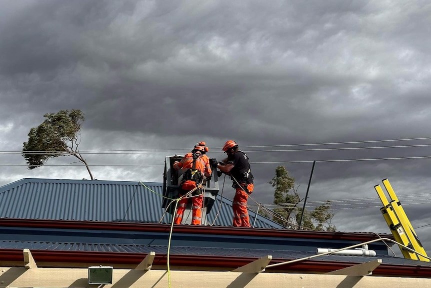 An image of SES workers on top of a house fixing an appliance