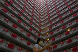 A woman walks past the Chinese and Hong Kong flags hanging from a residential building 